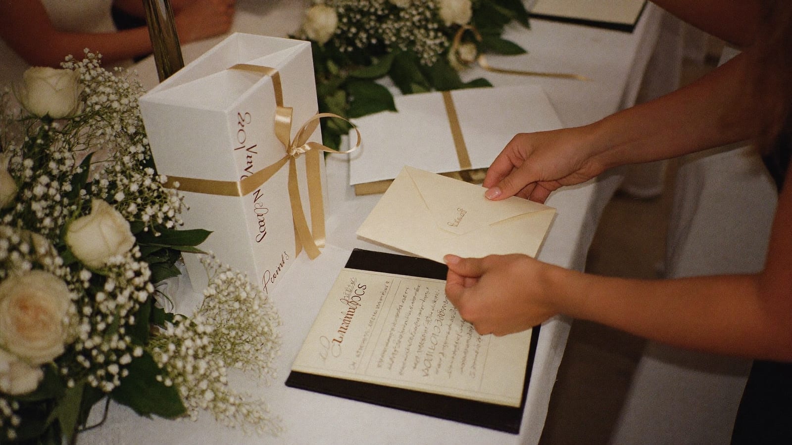 Invitat punând plicul cu darul de nuntă în cutia decorată de pe masa de la intrare, lângă cartea de urări
